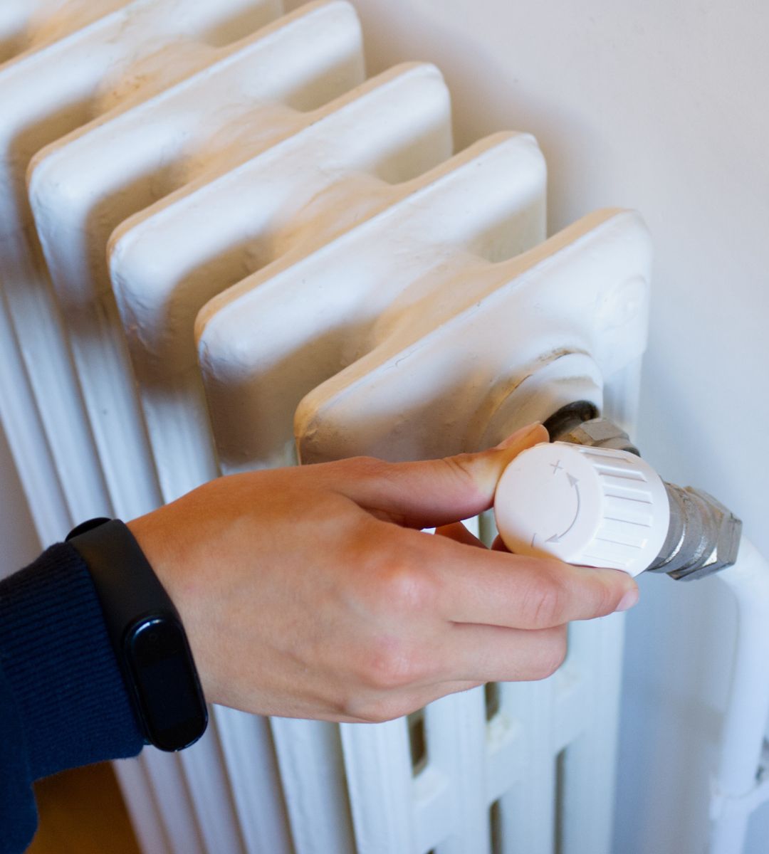 Zimowe świadczenia w UK na sezon 2025/2026 Foto: osoba ustawiająca termostat na kaloryferze