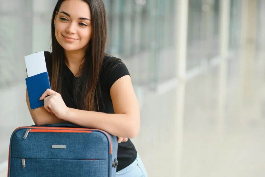 Jak znaleźć bilety lotnicze za mniej niż 70 zł Foto: kobieta z walizka i biletem lotniczym w ręce