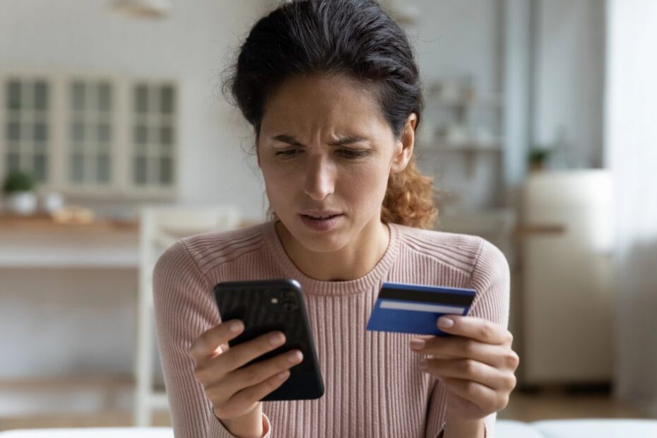 Poważna awaria w dużym banku - dotkniętych zostało setki klientów. Na zdjęciu kobieta z kartą płatniczą w ręku patrzy z zaniepojoniem w ekran telefonu