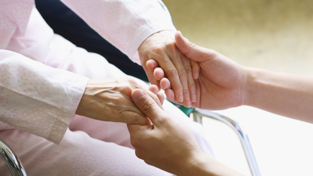 Skutki uboczne szczepionki AstraZeneca Foto: dłonie chorego trzymane przez drugą osobę