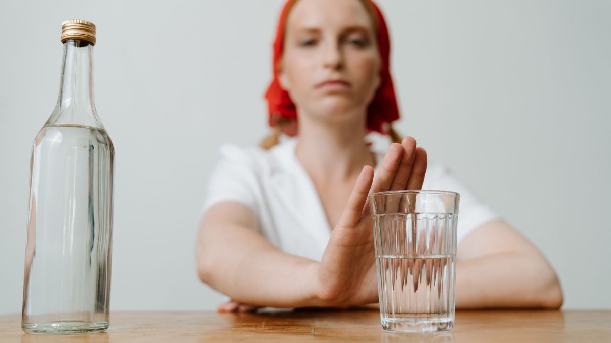 rezygnacja z alkoholu Foto: kobieta odmawiająca alkoholu, pusta szklanka i pusta butelka