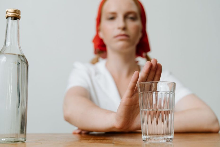 rezygnacja z alkoholu Foto: kobieta odmawiająca alkoholu, pusta szklanka i pusta butelka
