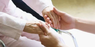 Skutki uboczne szczepionki AstraZeneca Foto: dłonie chorego trzymane przez drugą osobę