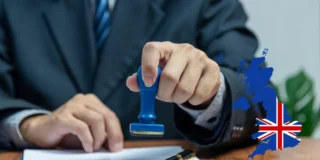 Home Office wysyła pisma nakazujące opuszczenie kraju Foto: ręce urzędnika stawiającego pieczątkę na dokumentach