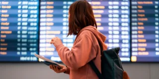 Chaos na europejskim lotnisku Foto: kobieta przed tablica odlotów w hali lotniska